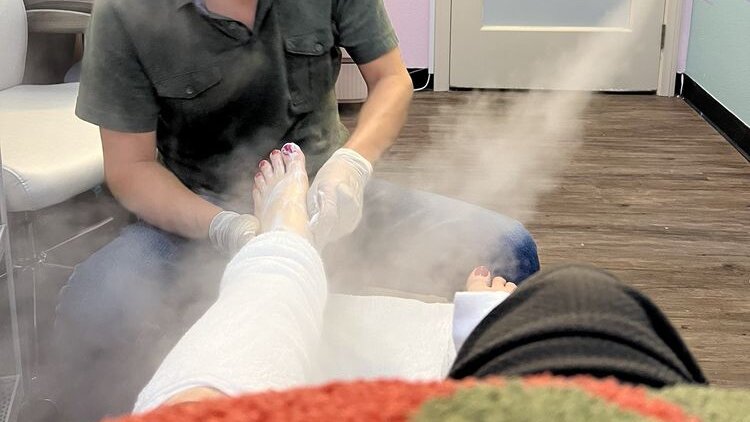 Nail technician in gloves giving a pedicure with steam