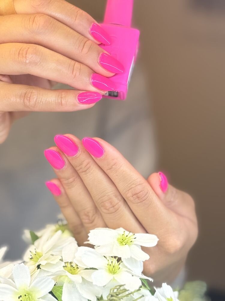 Hot pink nails next to a matching polish bottle